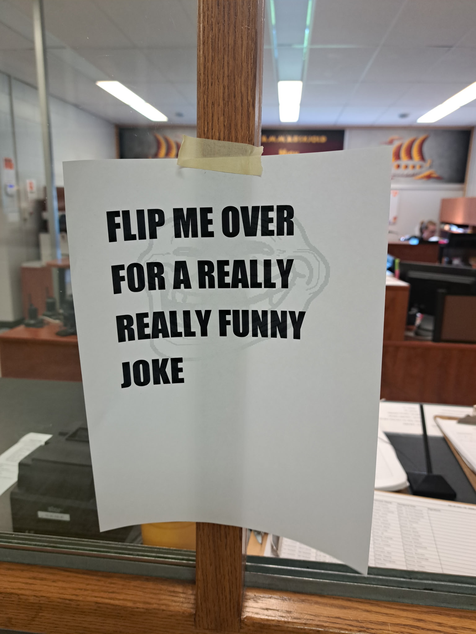 A sheet of paper that says “FLIP ME OVER FOR A REALLY FUNNY JOKE” where the light shining through from behind it reveals that a trollface is on the back 